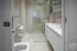 W łazience jasnobeżowe płytki stanowią tło dla bieli zabudowy i szkła.